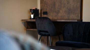 Un espace de bureau moderne comprenant un bureau, une chaise noire et une machine à café.