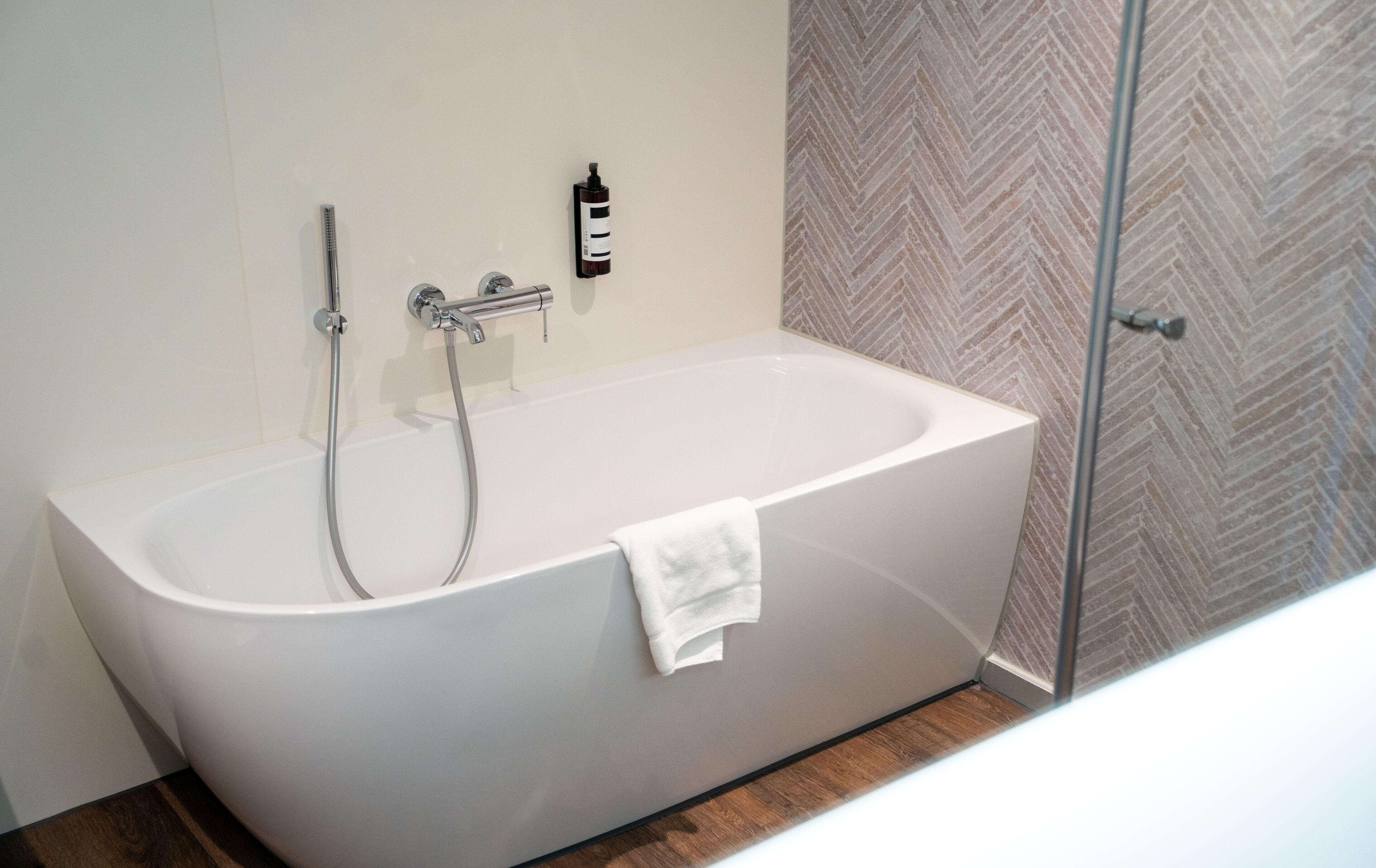 A modern bathroom with a freestanding bathtub, a handheld showerhead, and a glass-enclosed shower stall.