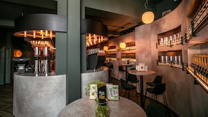 A modern bar area with round tables, bar stools, and a coffee machine. - Hampshire Hotel - Voncken Valkenburg (Valkenburg aan de Geul)