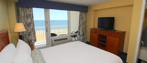Una habitación de hotel con una cama grande, televisión, escritorio y vista al mar.