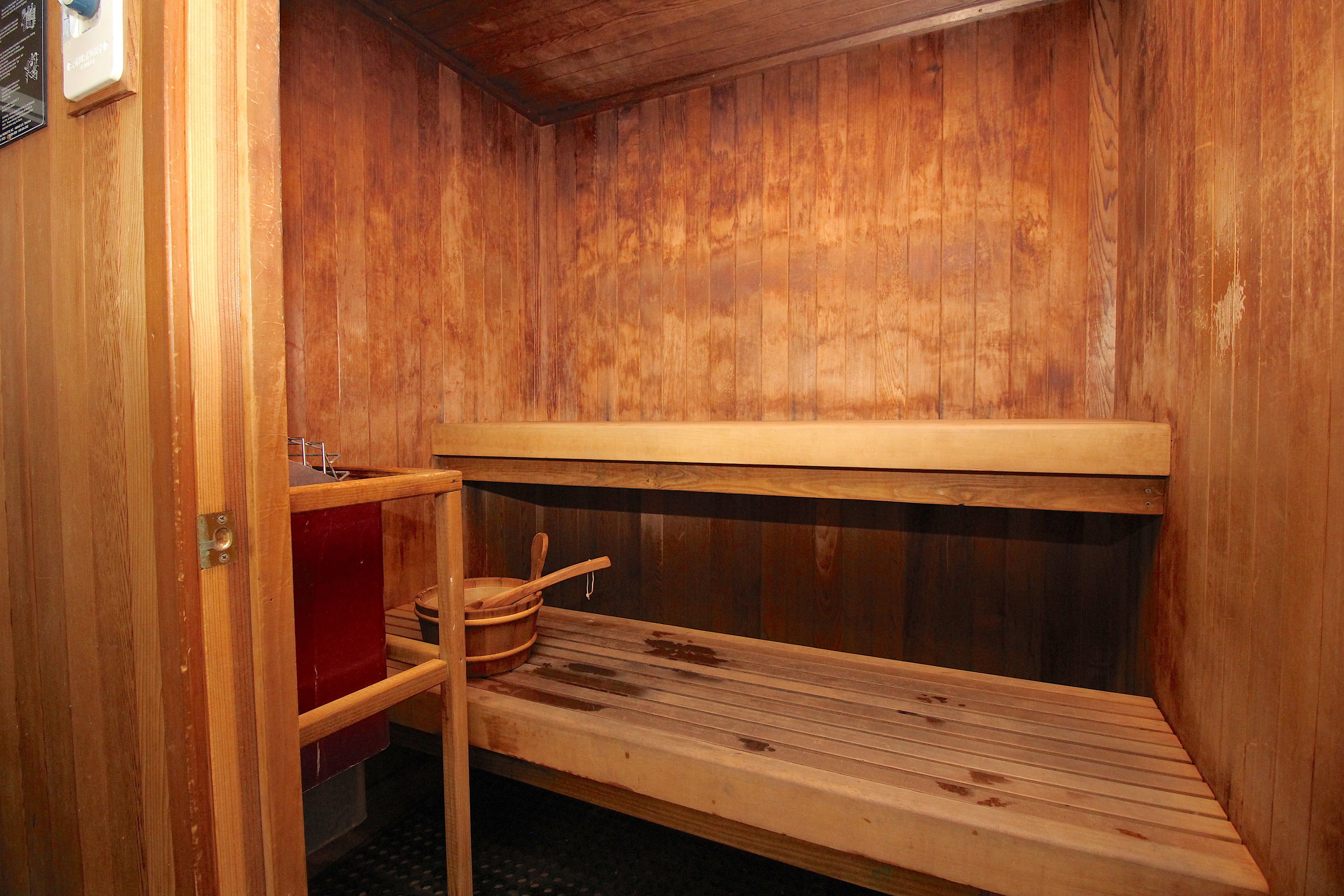 Una sauna in legno con panche e ripiano contenente un catino e un cucchiaio di legno.