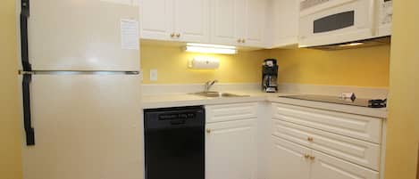 A compact kitchen with white cabinets, a built-in microwave, and a dishwasher.
