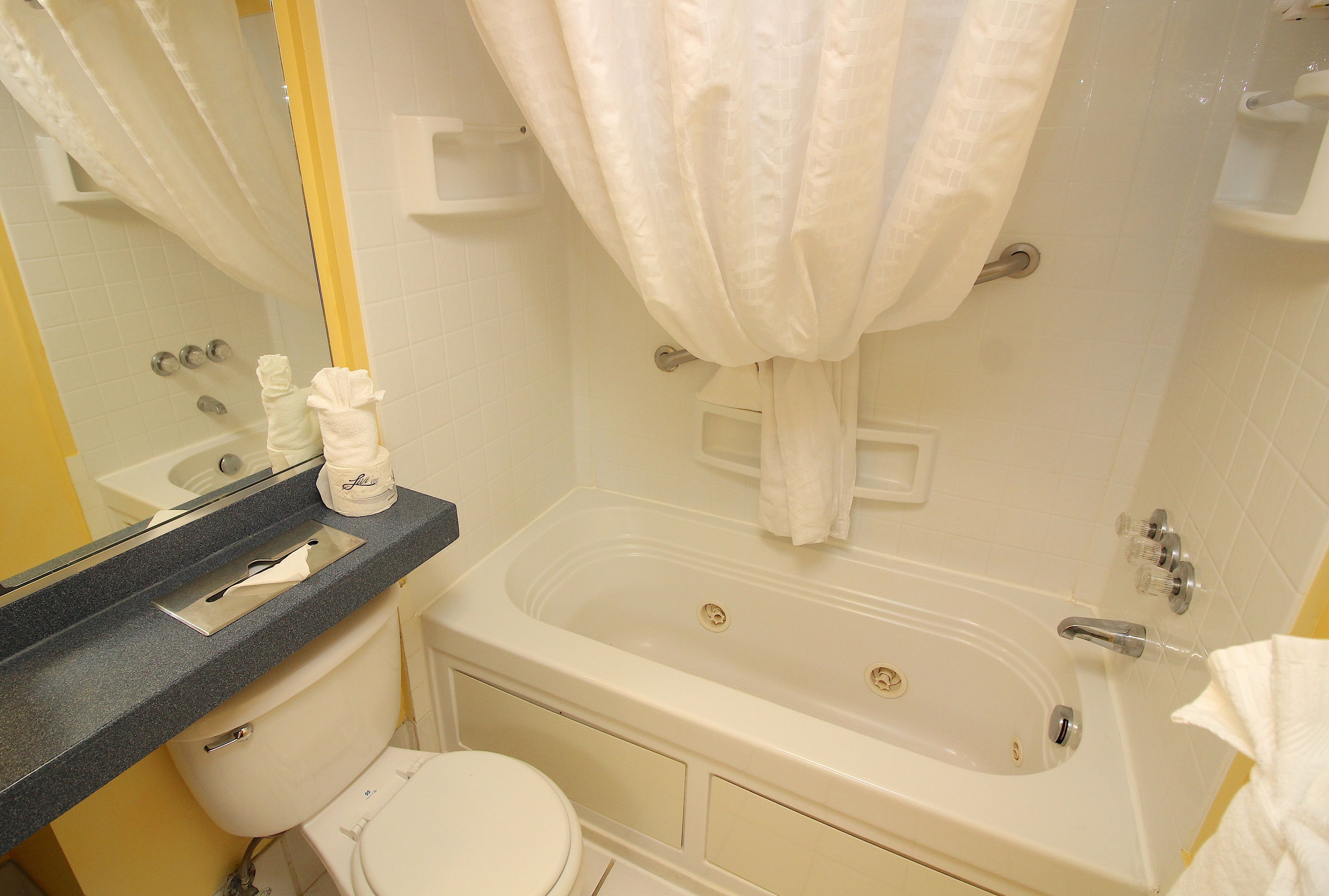 Un bany amb banyera, vàter i un lavabo amb barra de tovalloles.