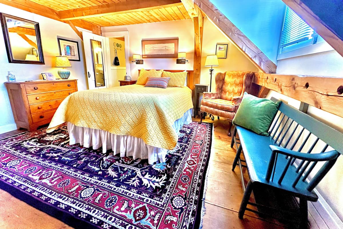 A bedroom with a large bed, a chair, a dresser, and a rug.