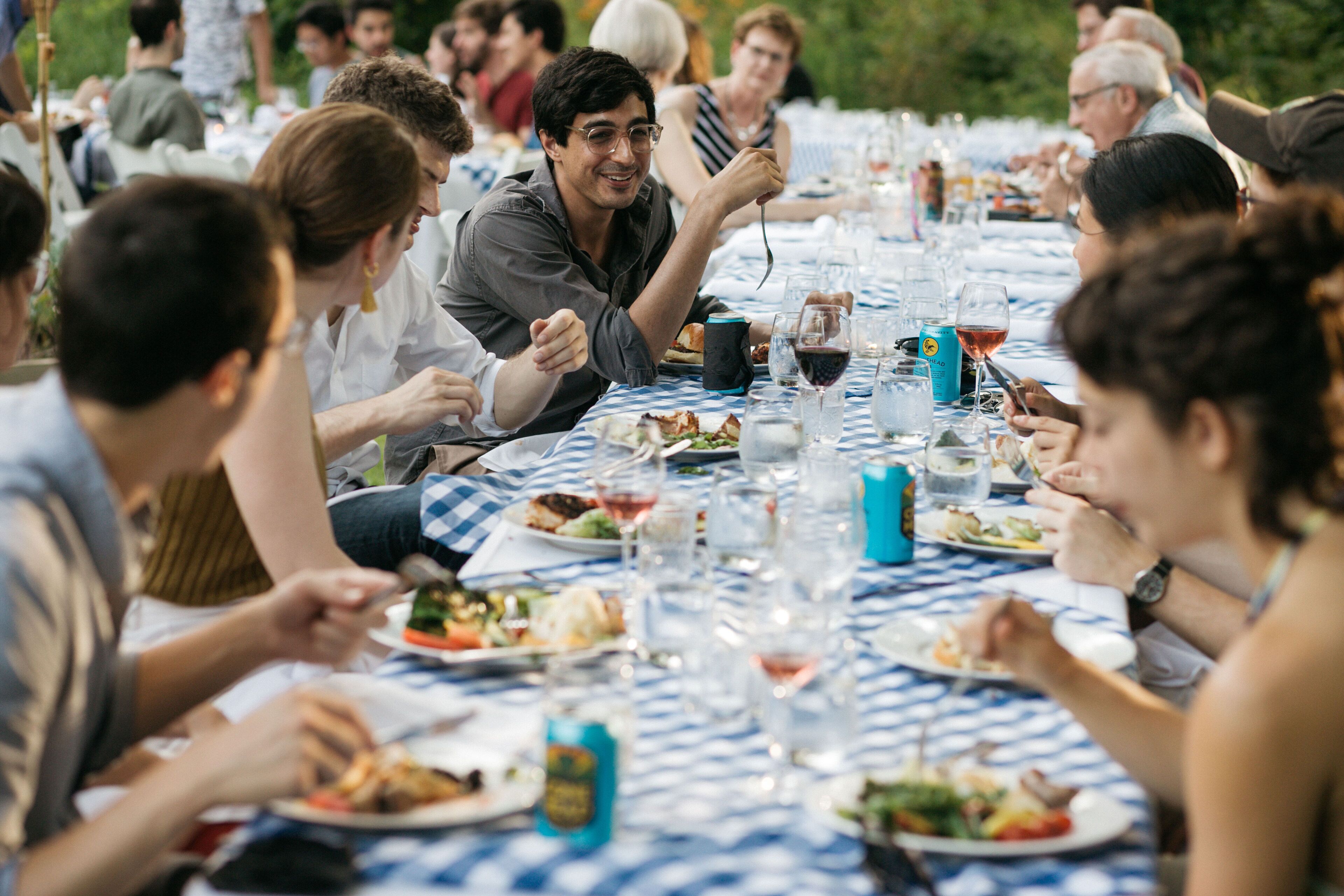 A group of people dining at an outdoor table with a checkered tablecloth.