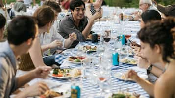 A group of people dining at an outdoor table with a checkered tablecloth.