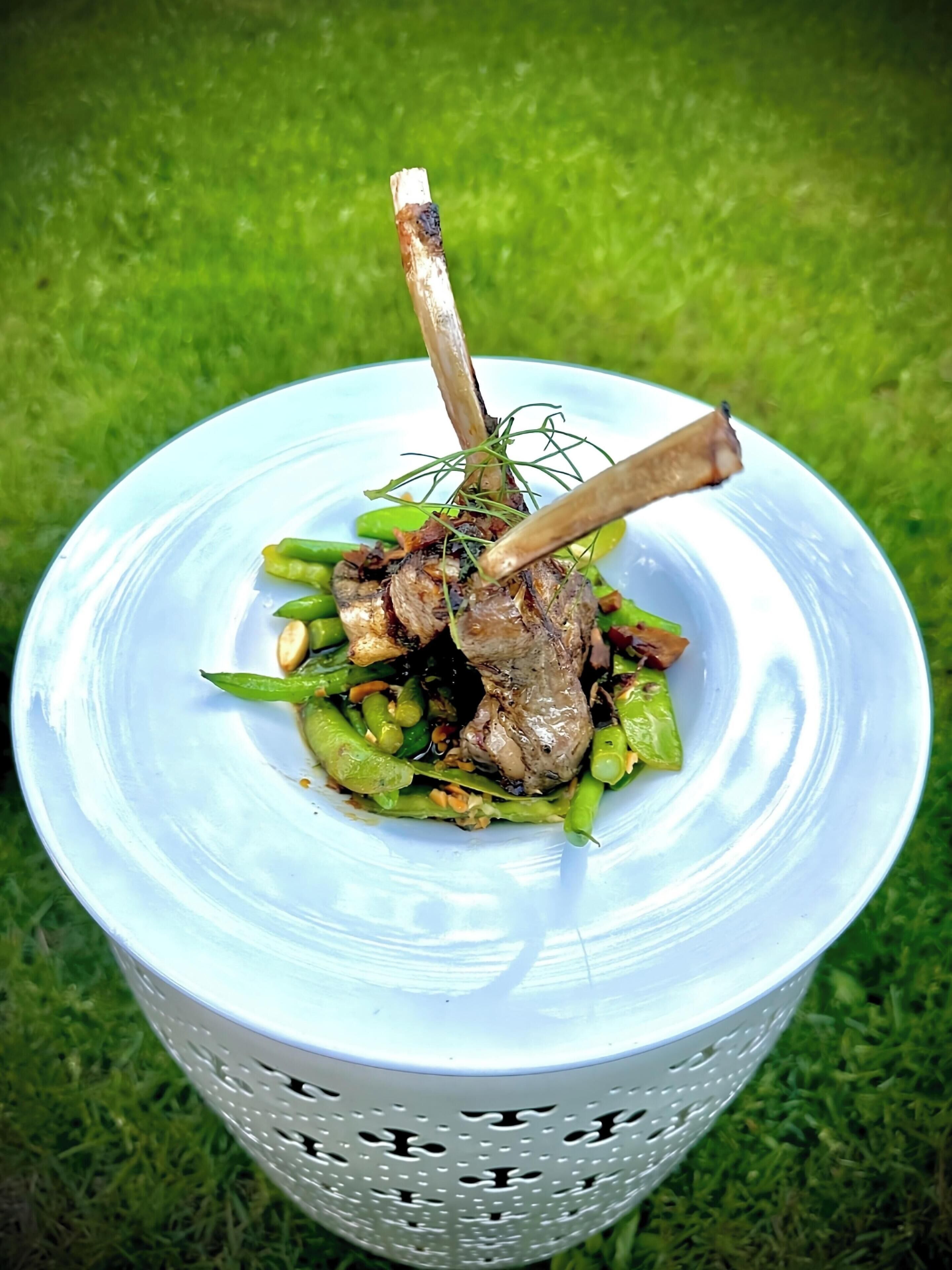 Un tazón blanco con asa que contiene un guiso de carne y verduras verdes.