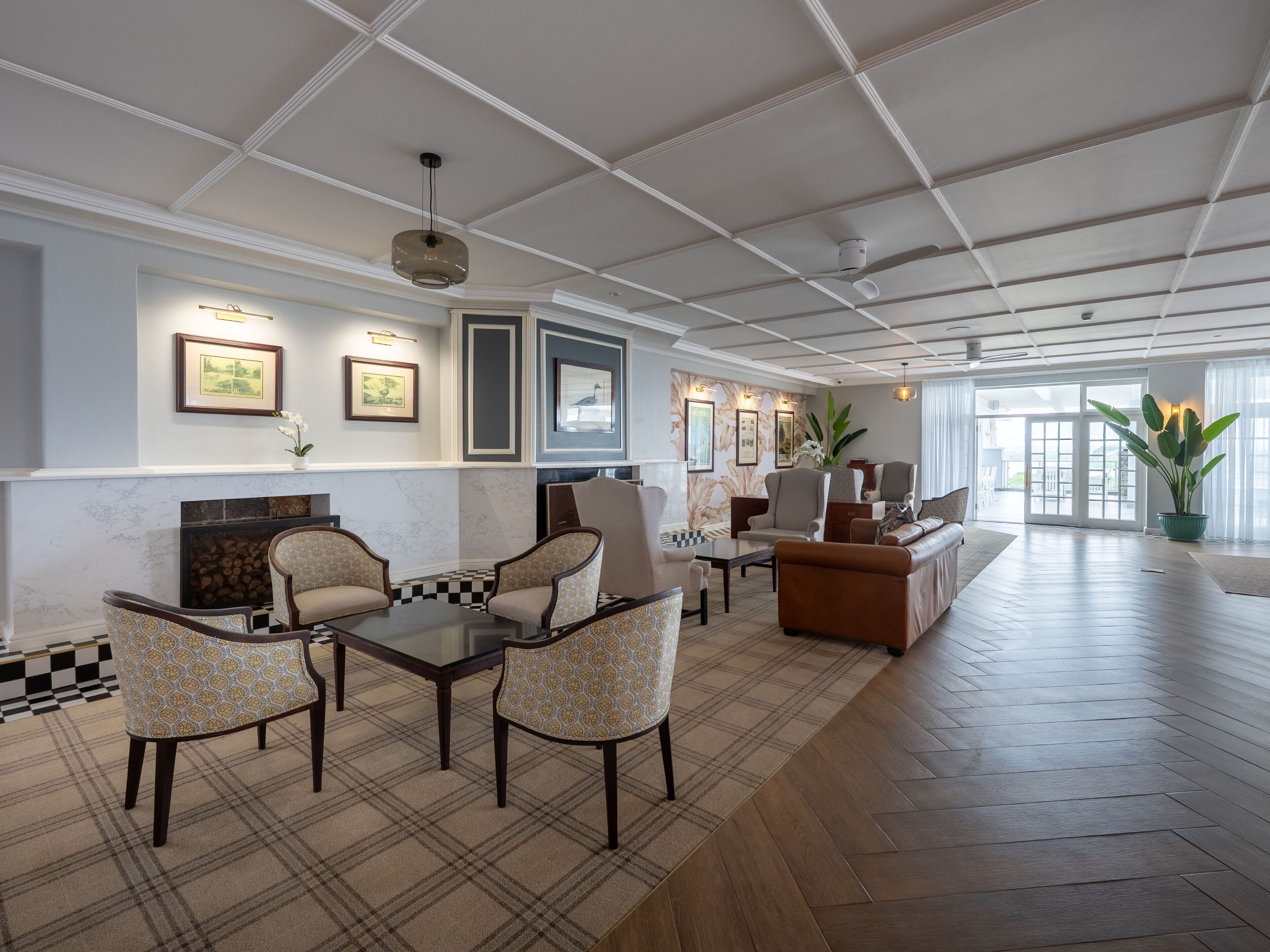 A spacious lobby with a checkered floor, a fireplace, and a seating area with patterned chairs and sofas.