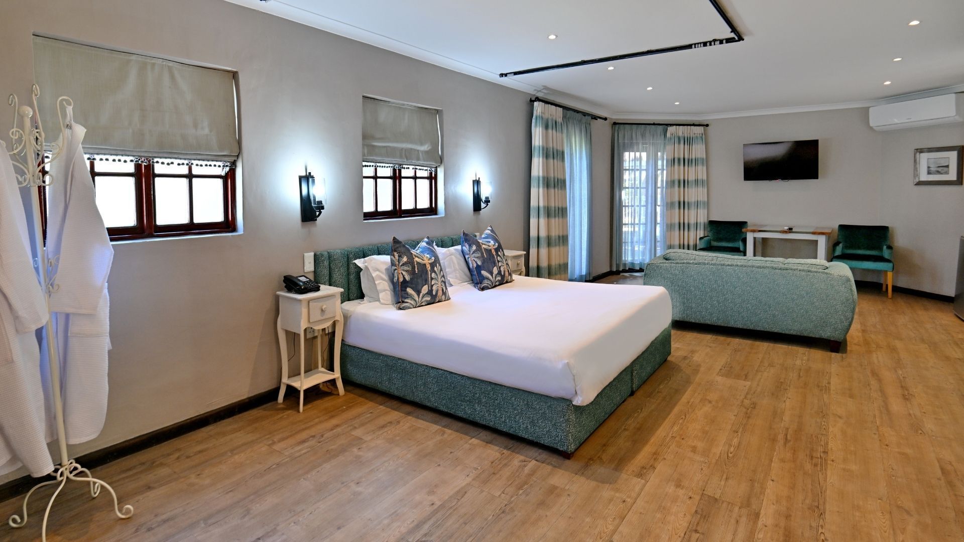 A hotel room with a large bed, a smaller bed, a desk, a chair, and a TV.