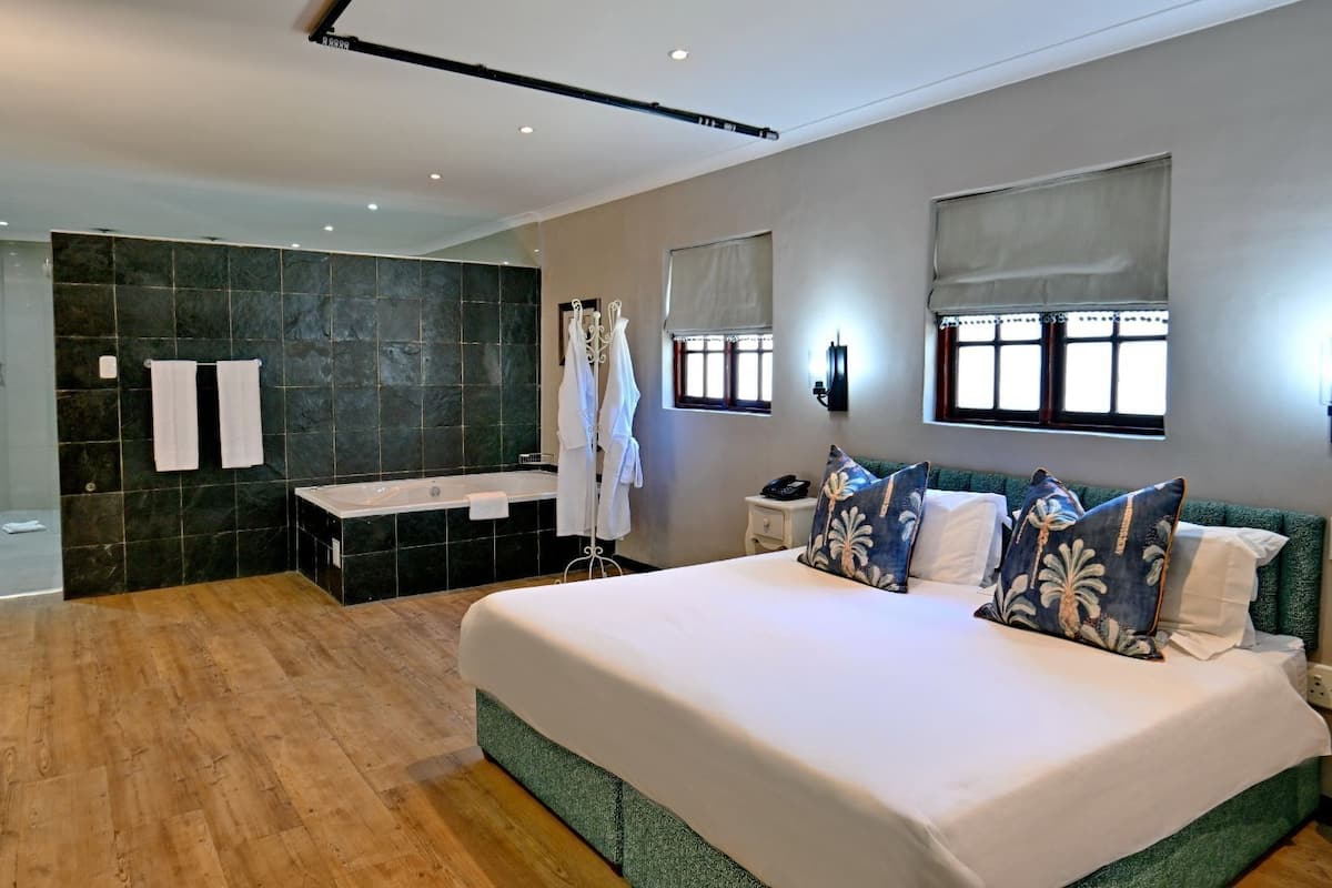 Une chambre d’hôtel moderne dotée d’un grand lit, d’une salle de bain séparée et offrant une vue sur la ville.