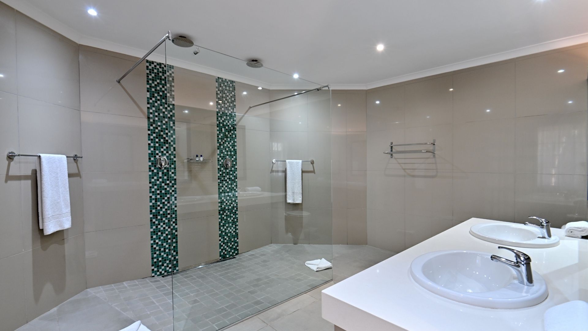A modern bathroom with a glass-enclosed shower, a large sink, and a mirror.