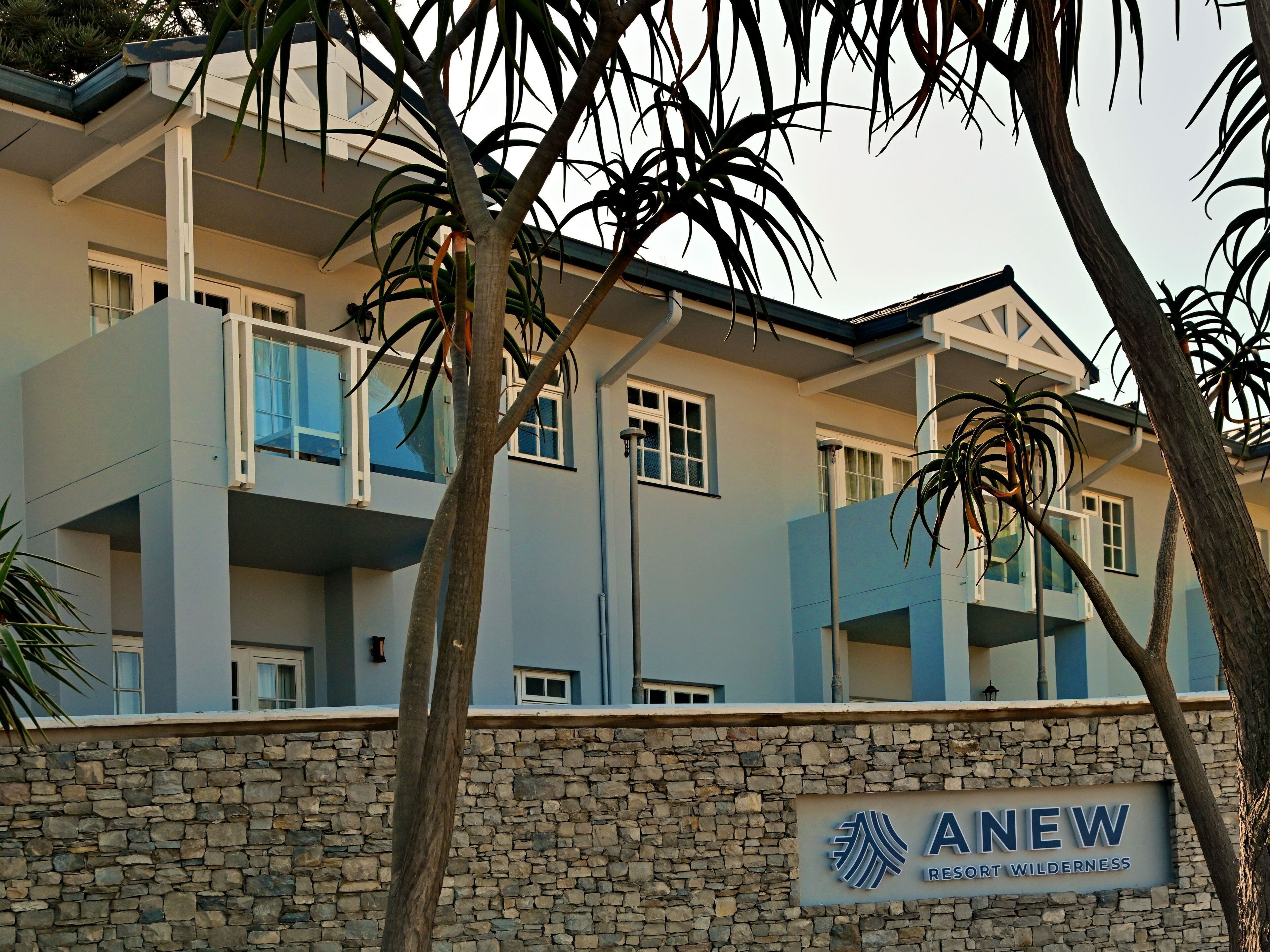 A multi-story building with a stone facade and balconies. A sign reads "ANew Resort Wilderness."