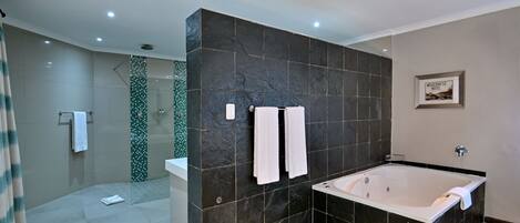 A modern bathroom with a large bathtub, a shower area, and a glass-enclosed shower.