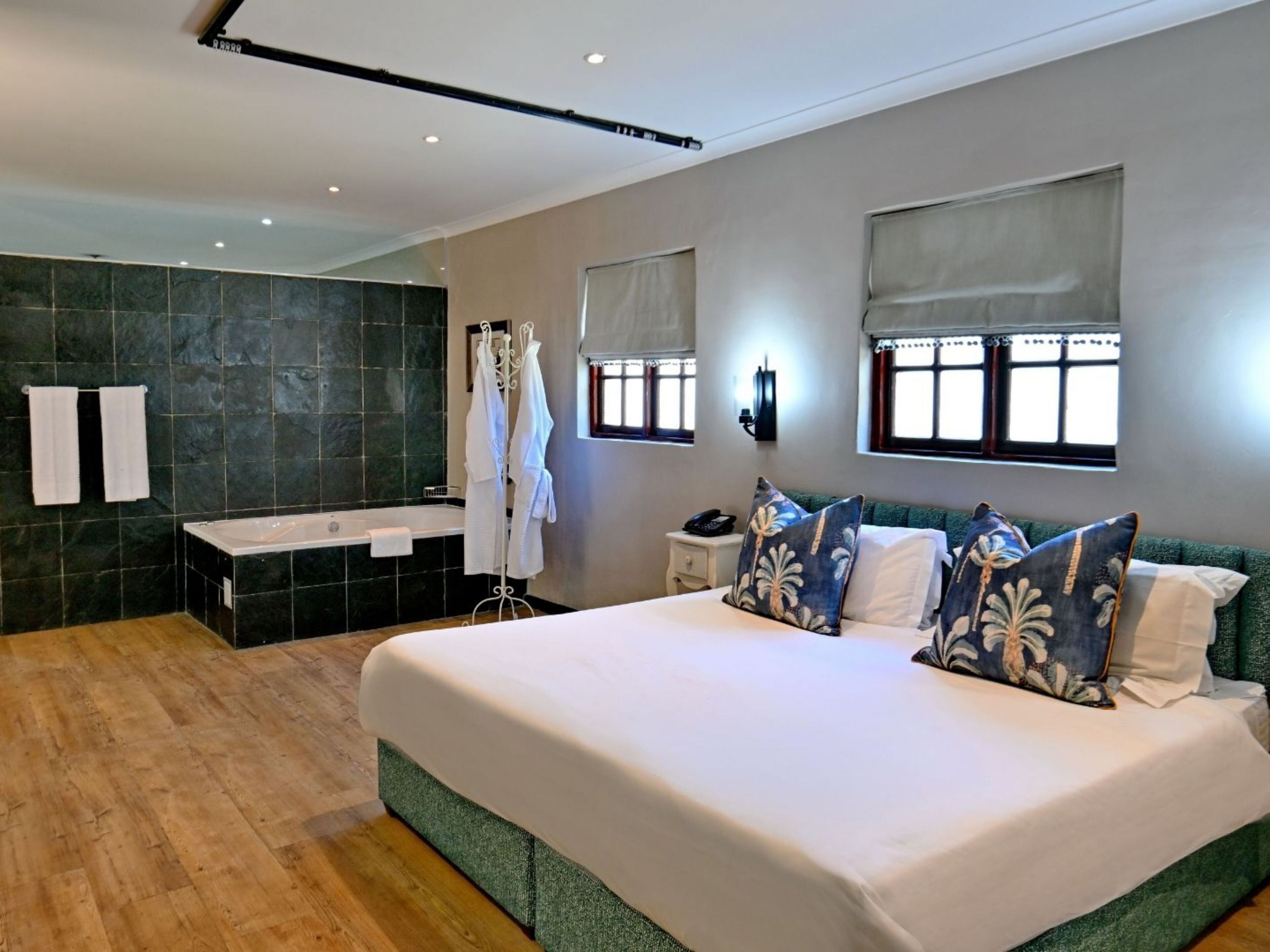 Une chambre d’hôtel moderne dotée d’un grand lit, d’une salle de bain avec baignoire et d’un espace douche.