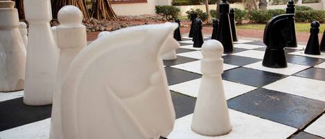 A chessboard with white and black pieces in an outdoor setting.