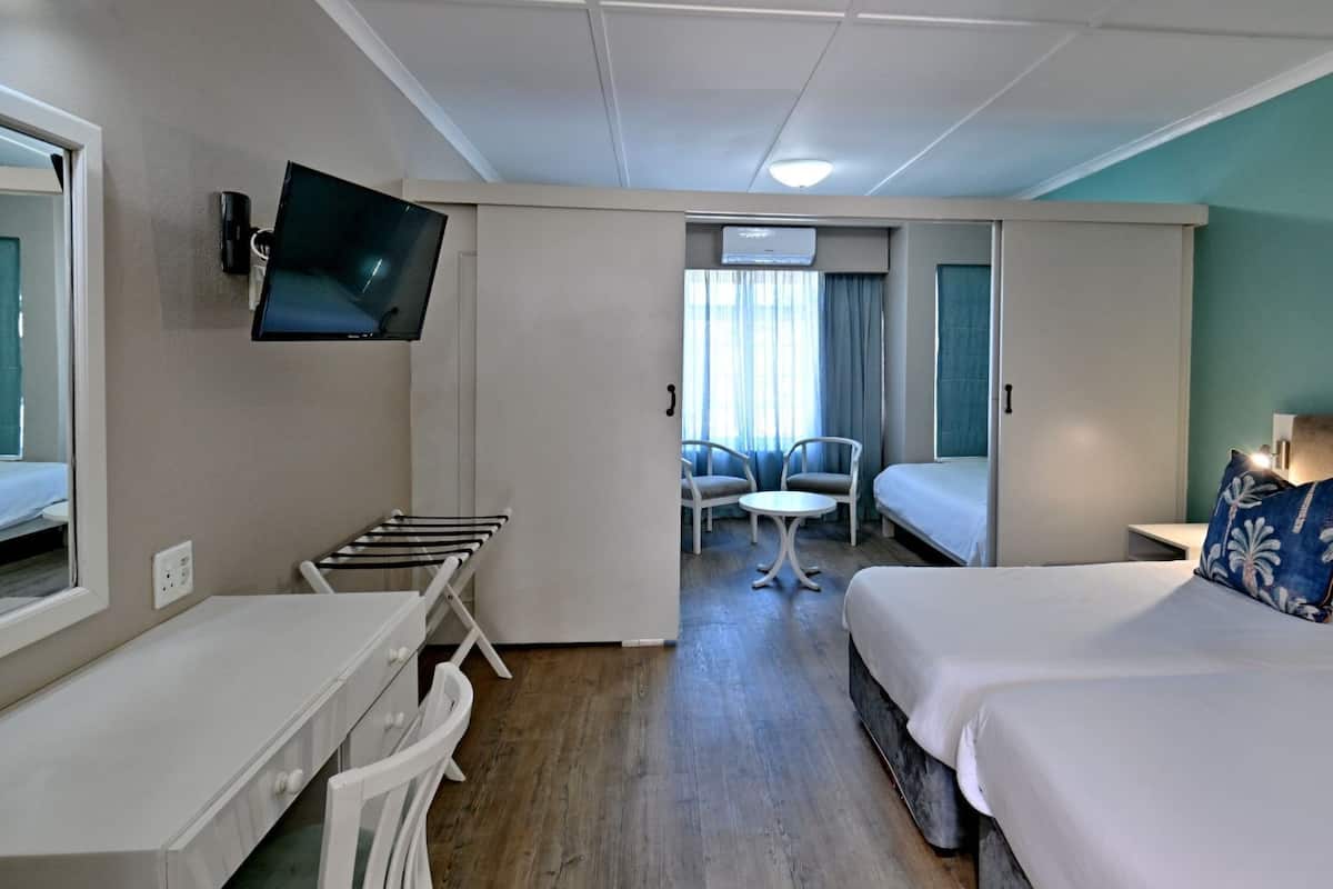 Une chambre d’hôtel avec un lit, un bureau, une chaise, une télévision et une fenêtre.