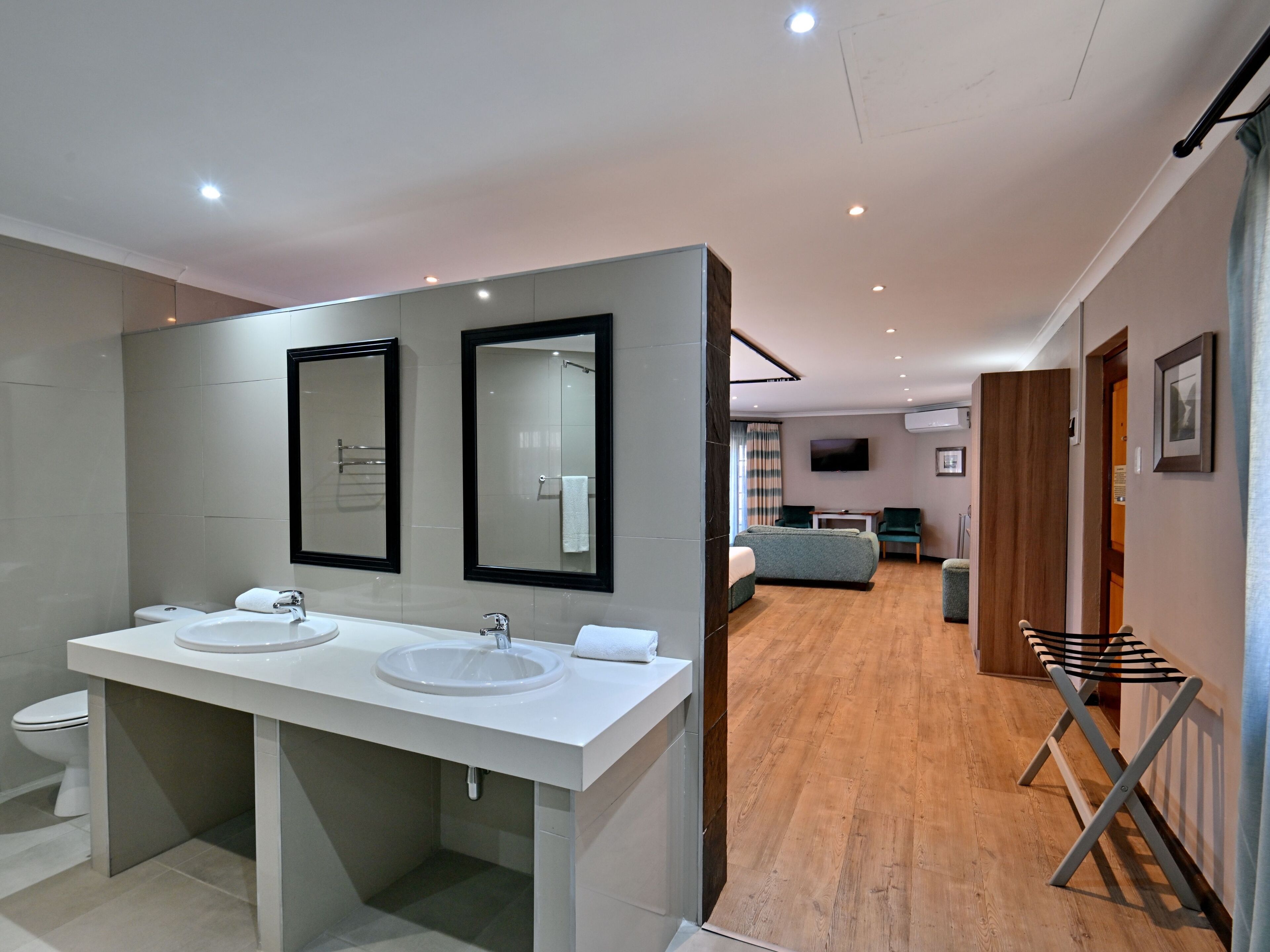 A modern bathroom with two sinks, a toilet, and a shower.