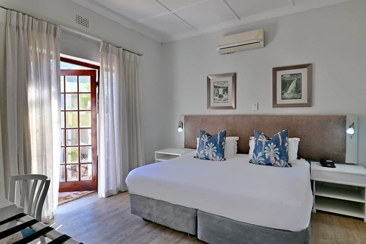 Une chambre d’hôtel avec un grand lit, deux tables de chevet, une chaise et une fenêtre avec des rideaux.