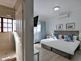 Habitación de hotel con una cama grande, televisión, ventilador de techo y ventana con cortinas.