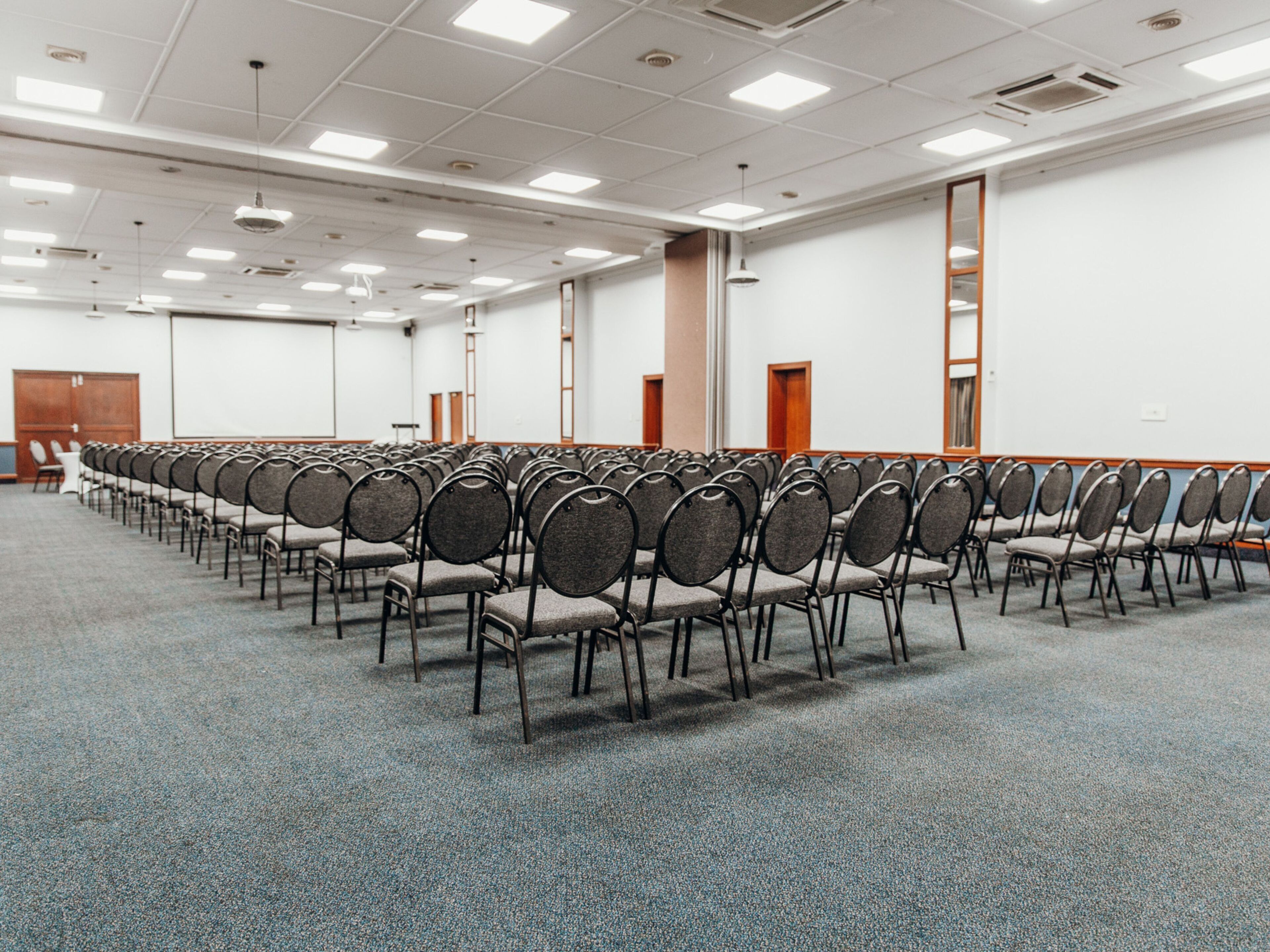 A conference room with rows of chairs, a carpeted floor, and a whiteboard on the wall.