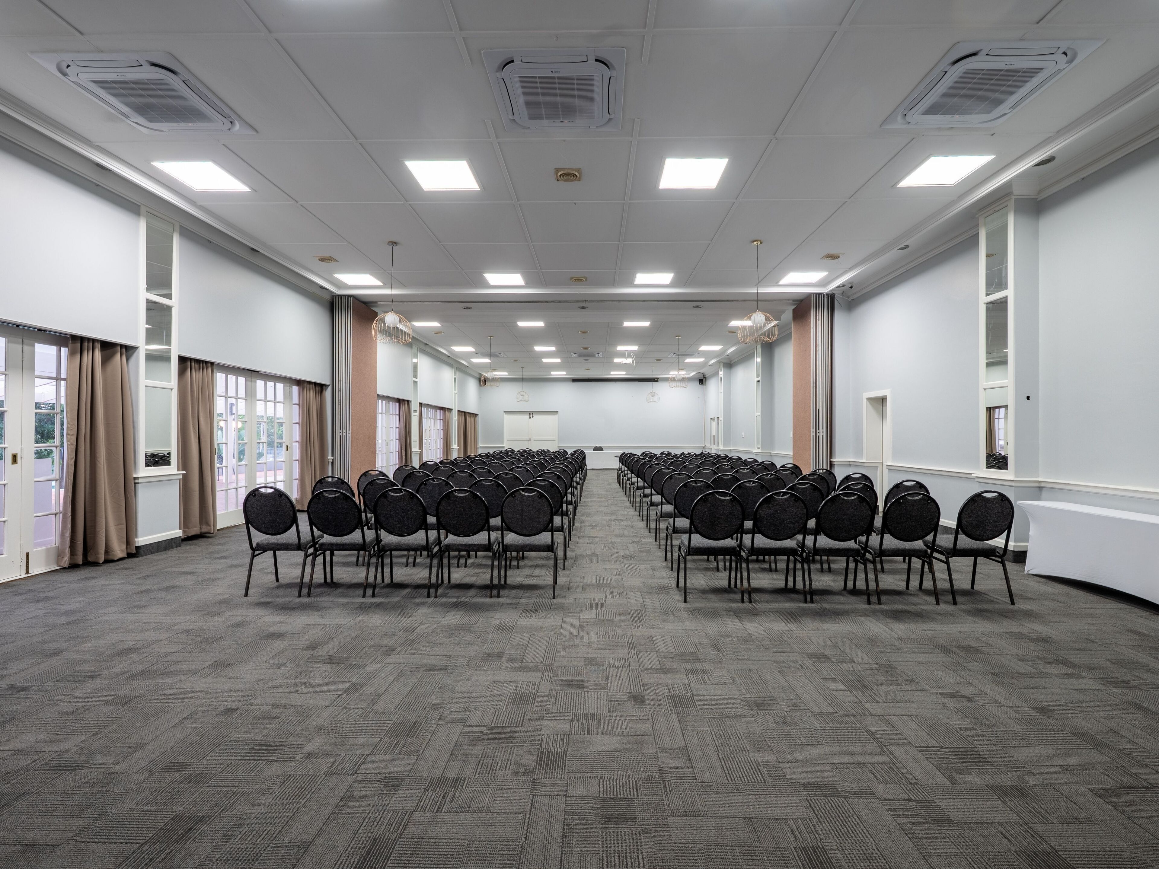 A large conference room with rows of chairs, white walls, and a carpeted floor.