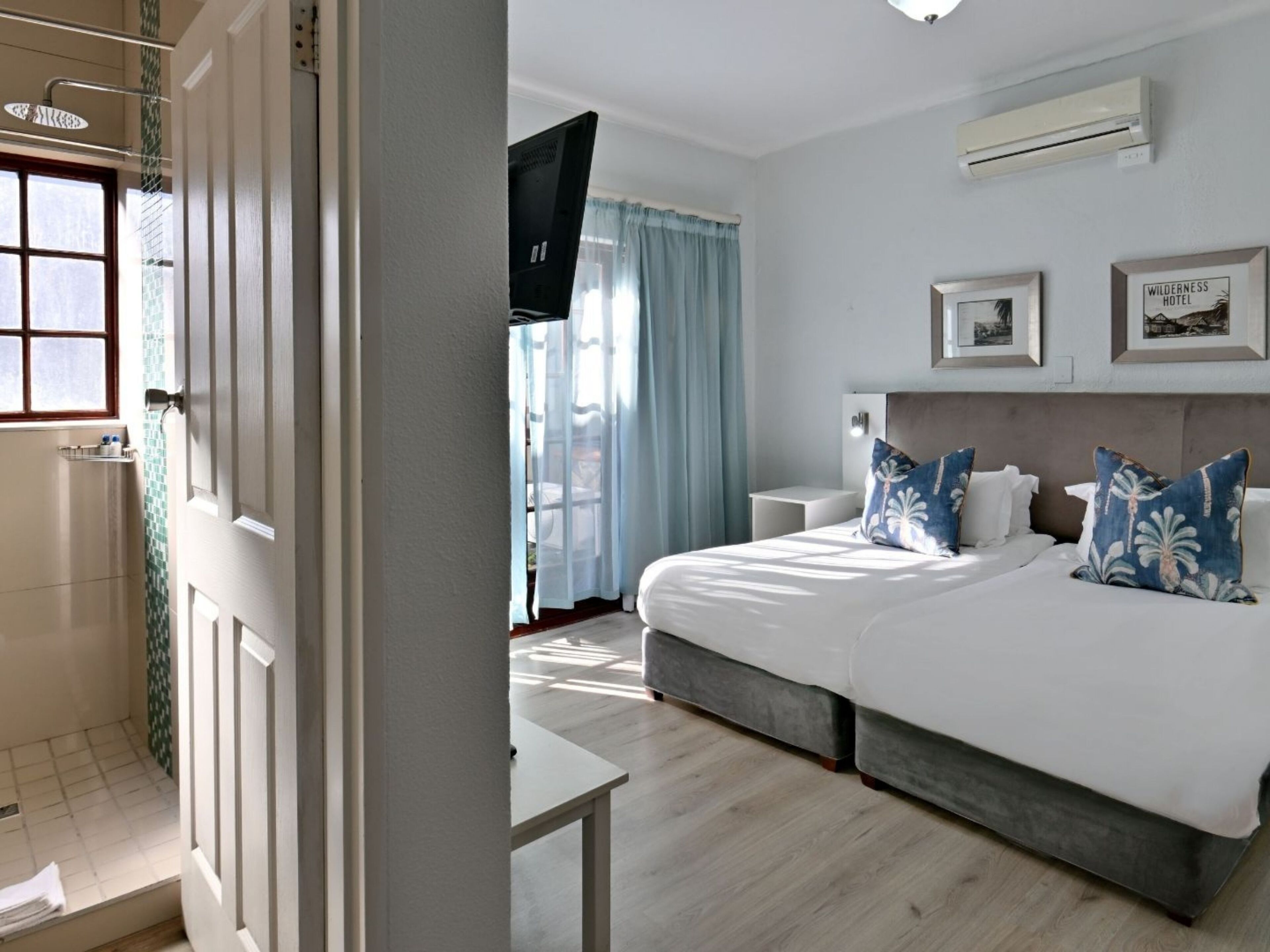 Une chambre d’hôtel moderne avec un grand lit, une table de chevet, une télévision et une fenêtre avec des rideaux.
