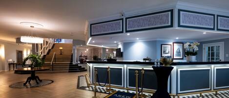 Un vestíbulo de hotel con una recepción, una escalera y un mostrador de check-in.
