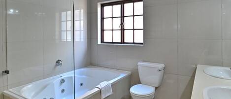 Een moderne badkamer met een glazen douchecabine, een vrijstaand bad, een toilet en een wastafel.