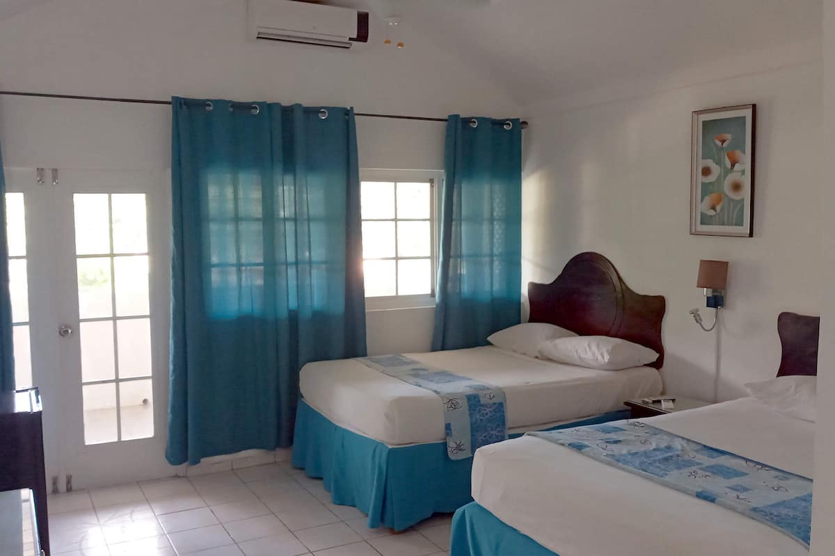 A bedroom with a bed, a bedside table, a lamp, and a window with curtains.