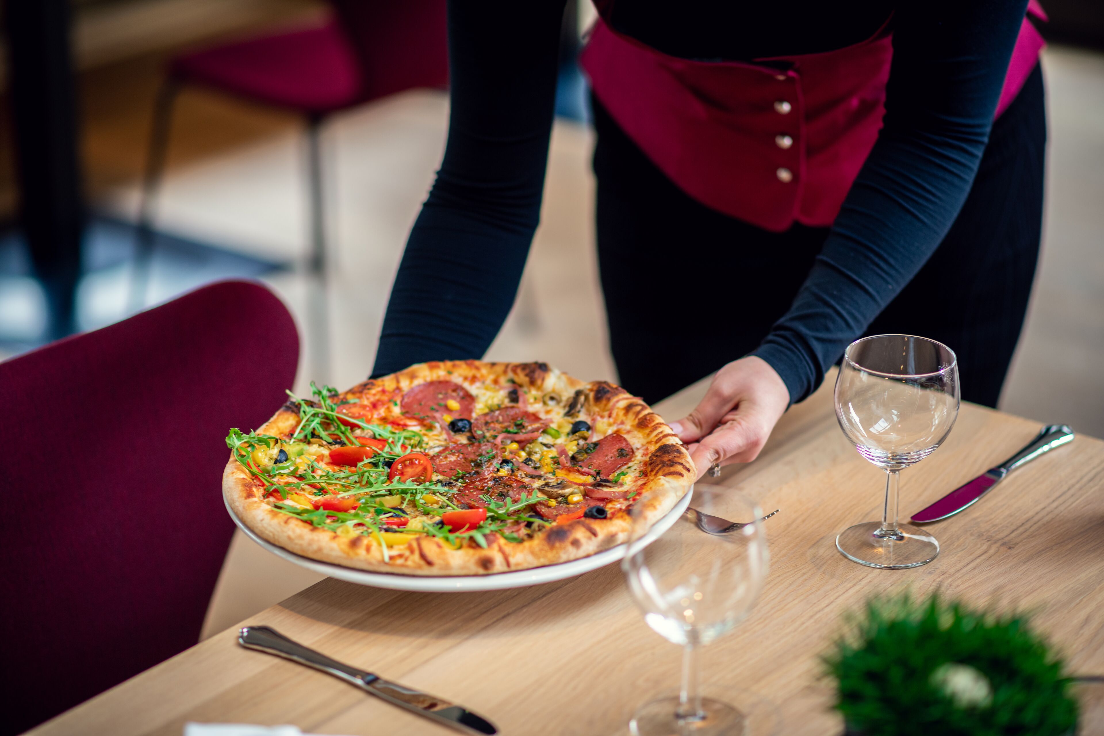 Una pizza en un plato con una copa de vino y un cuchillo sobre una mesa.