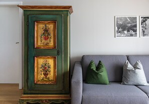 Um armário verde com desenhos elaborados e um sofá cinza com duas almofadas.