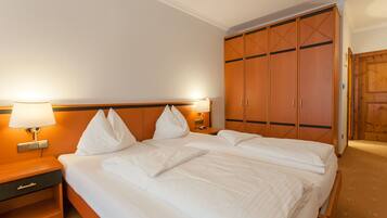 Quarto de hotel com cama grande, duas mesas de cabeceira e um guarda-roupa.