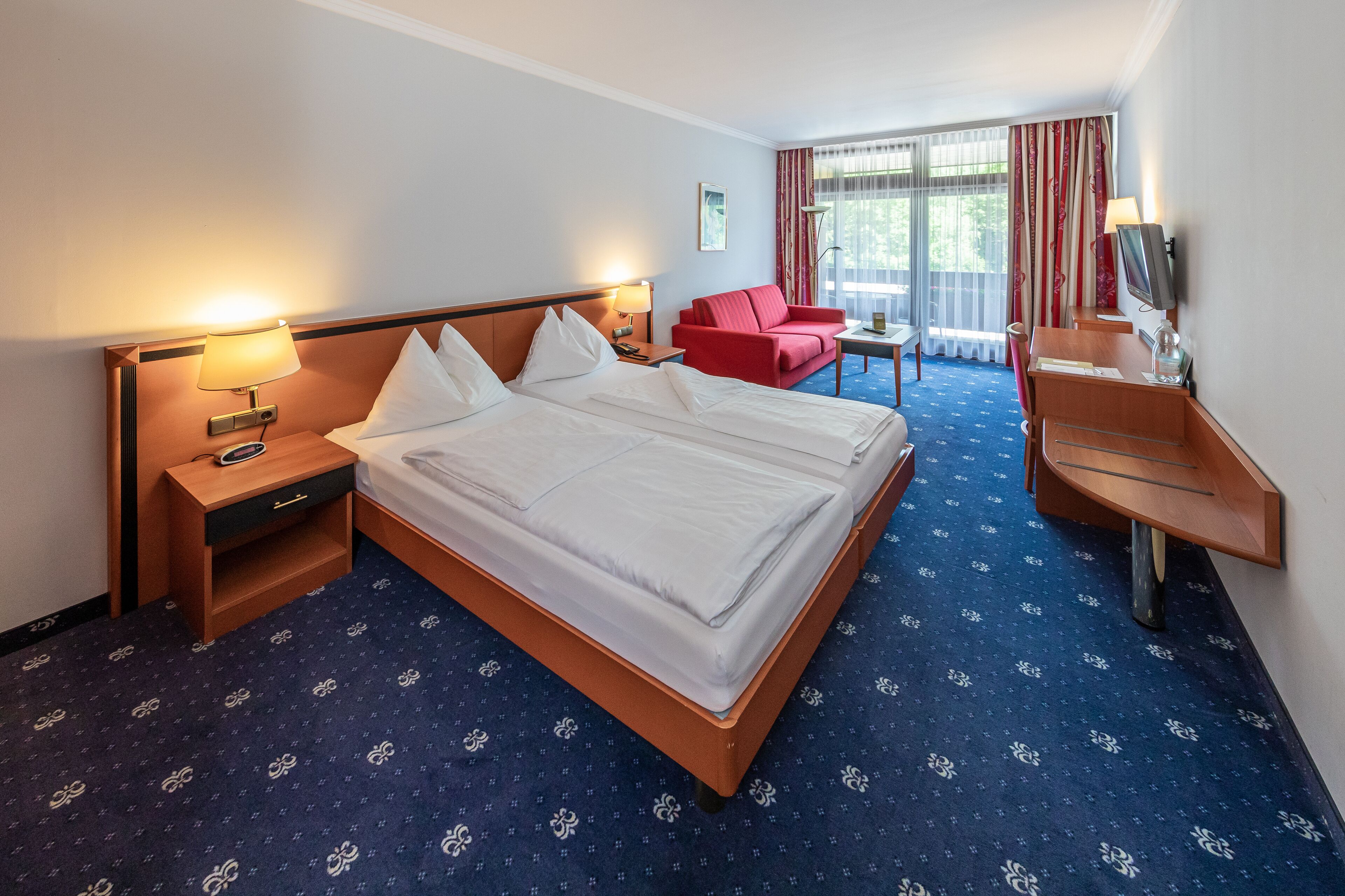 Una habitación de hotel con una cama grande, un escritorio, una silla y un televisor.