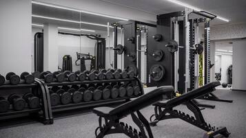 Une salle de sport équipée de matériel de musculation, notamment des haltères et un banc.