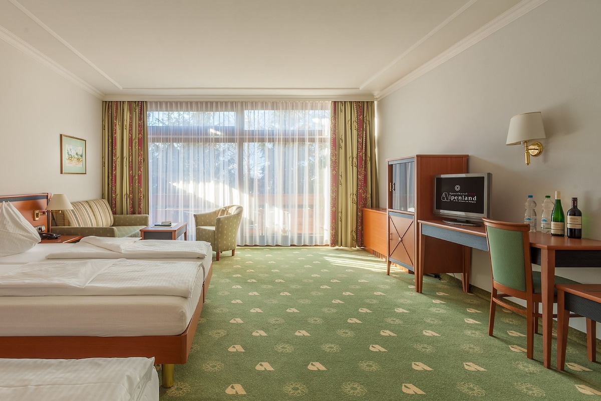 Quarto de hotel com duas camas, uma escrivaninha, uma televisão e uma cadeira.