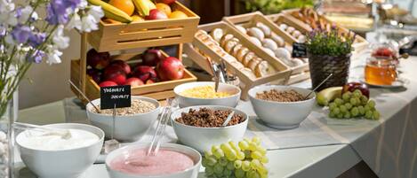 A buffet with various food items including fruits, yogurt, and granola.