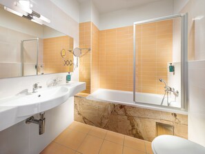 A bathroom with a white sink, mirror, and bathtub. - Hotel Michael (Prague)