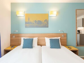 A hotel room with two beds, a cityscape painting, bedside lamps, a nightstand, and a mirror. - Aparthotel Adagio Access La Défense Place Charras (Courbevoie)