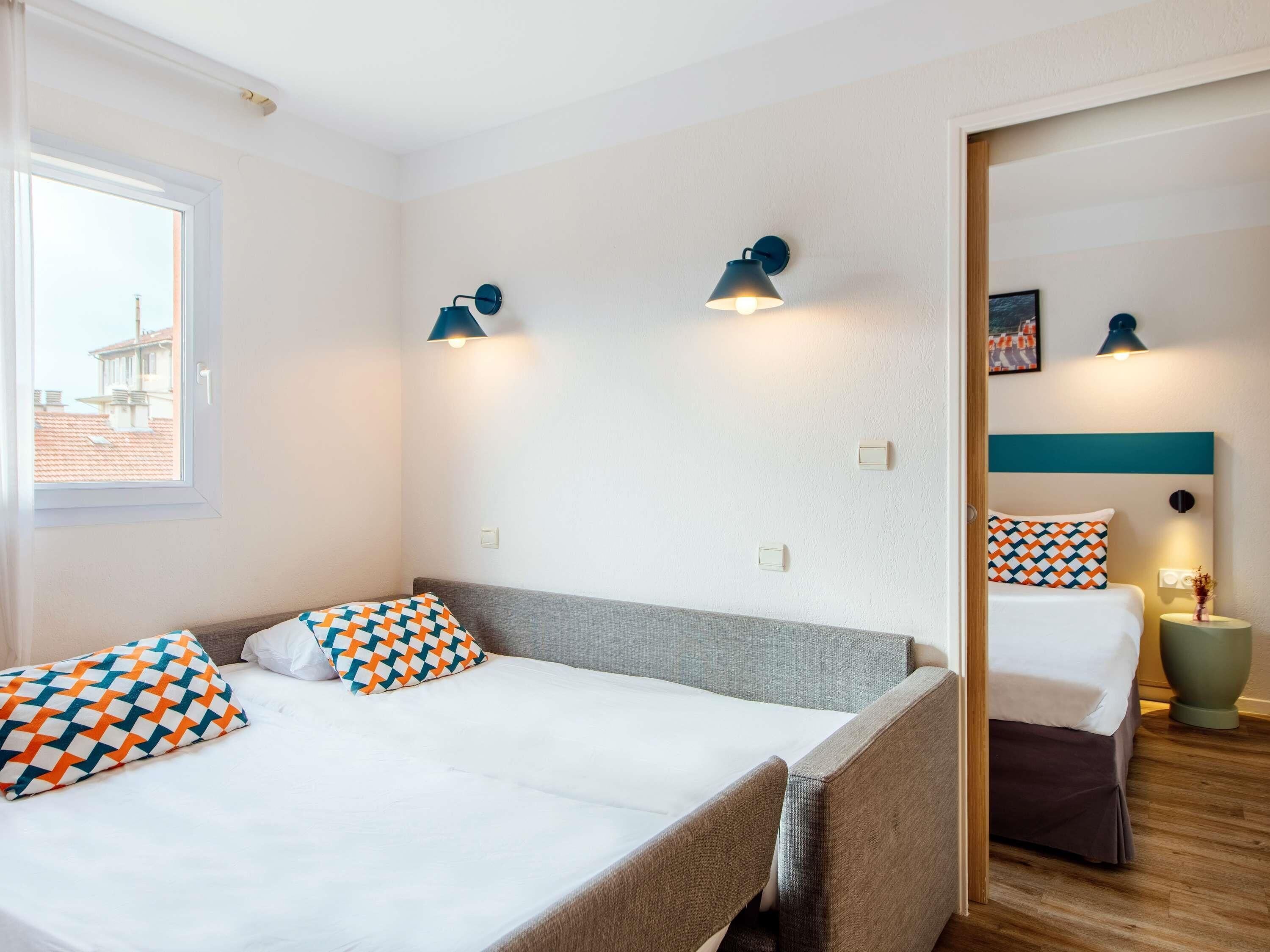 Een hotelkamer met twee bedden, een raam en wandlampen.