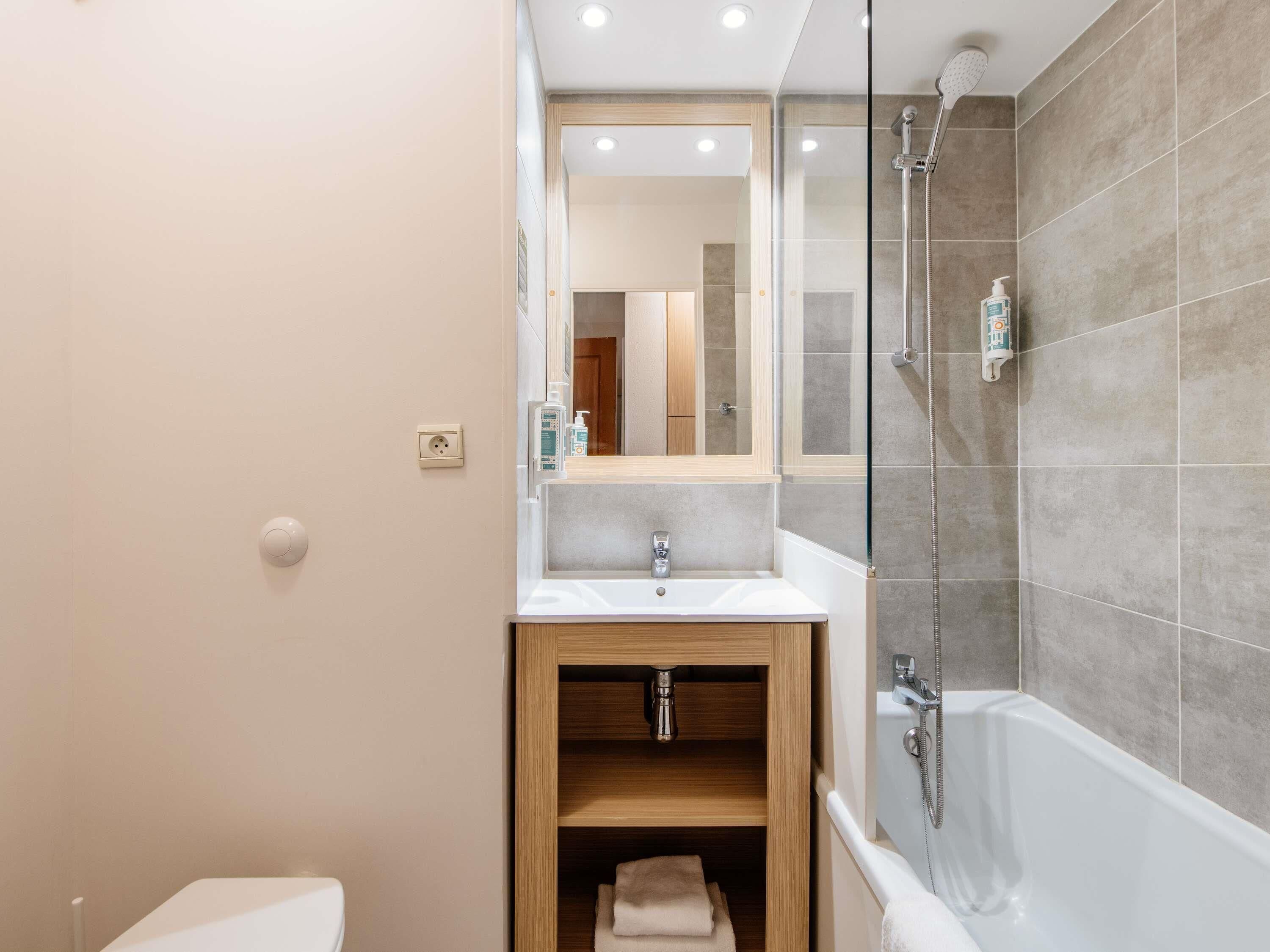 Une salle de bain moderne avec une douche à parois de verre, un meuble-lavabo en bois et une étagère intégrée.