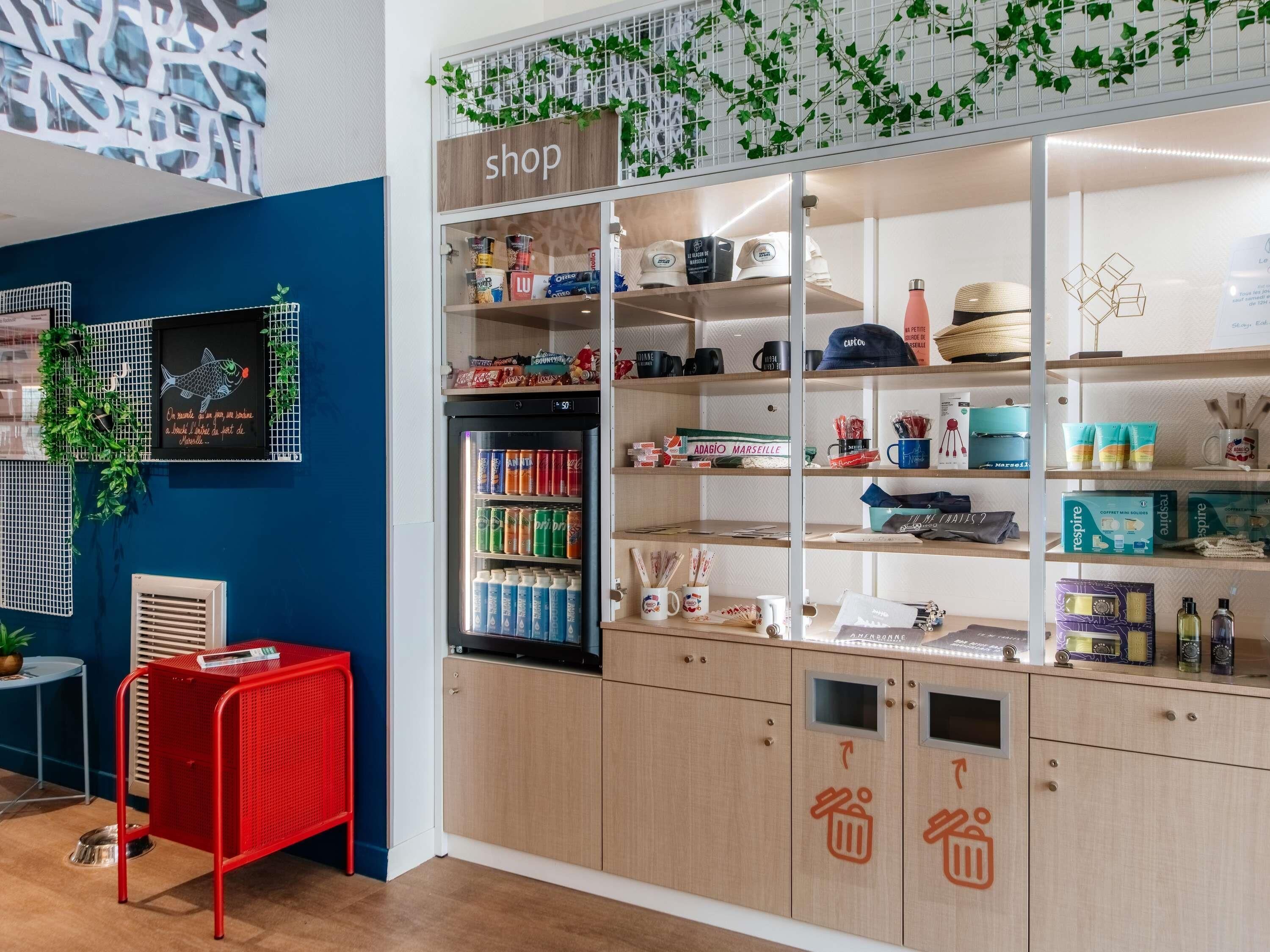 A kitchenette with a fridge stocked with beverages, a coffee machine, and a small table with a chair.