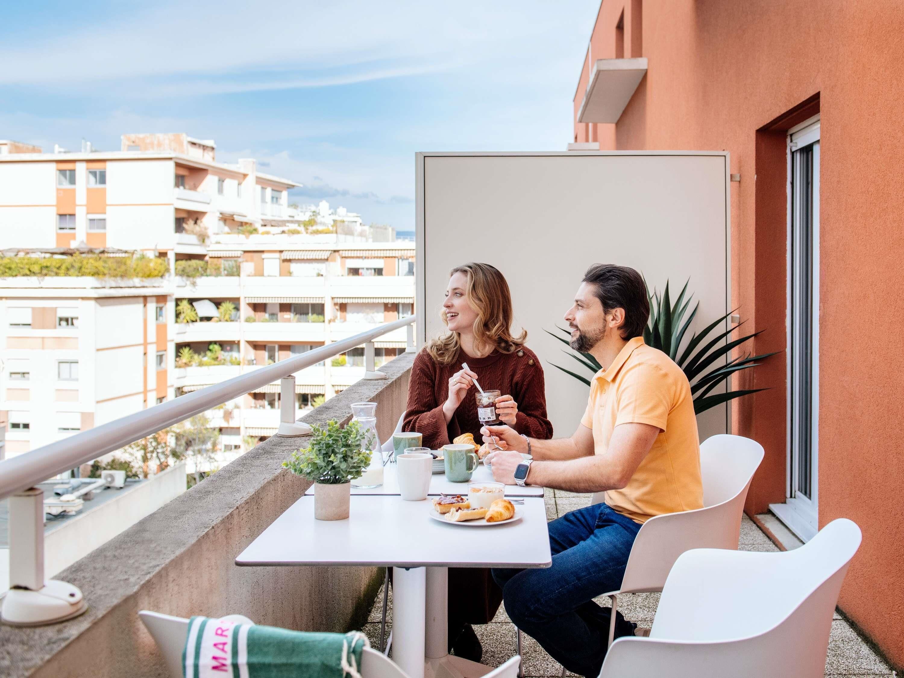 Un balcón con una mesa, sillas y una planta en maceta.