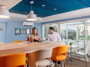 Ein modernes Büro mit blauer Decke, einem hölzernen Empfangstresen und orangefarbenen Stühlen.