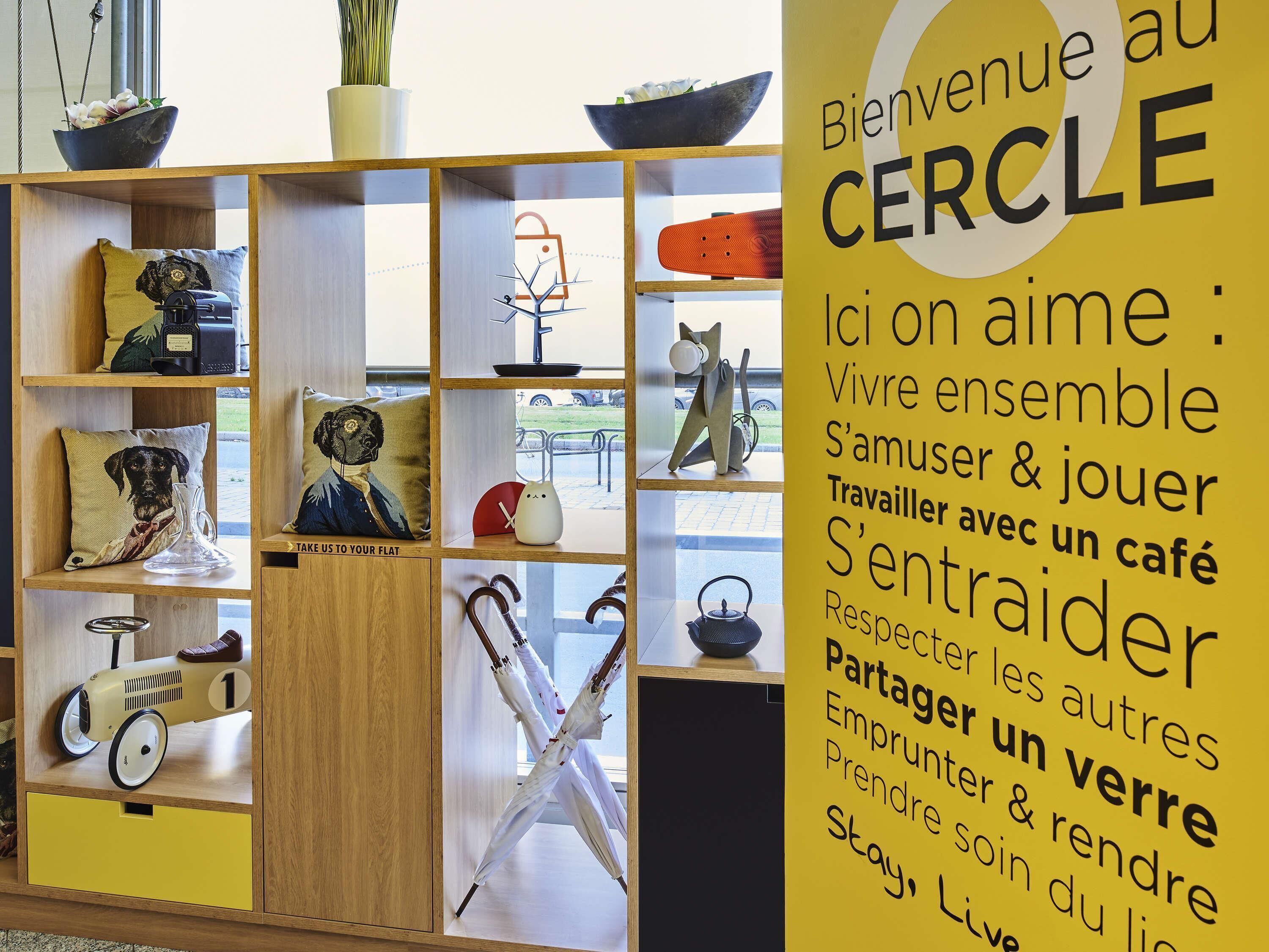 A room with a wooden shelf displaying various items like a dog pillow, a vintage car, and a cat sculpture.