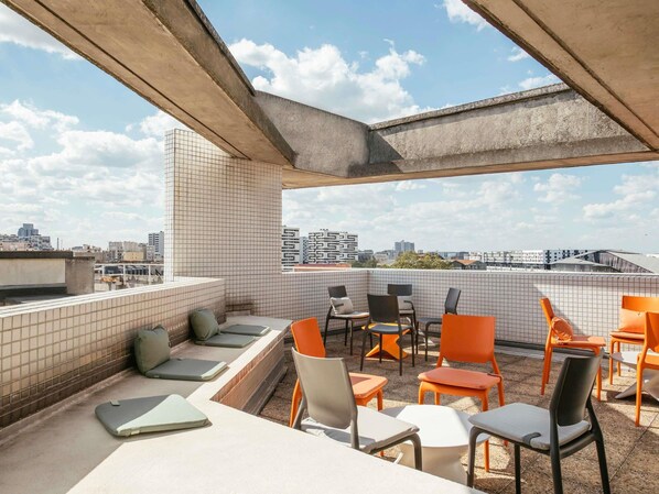 A rooftop terrace with tiled walls, outdoor seating, and a city view.