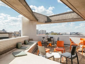 Terraza en la azotea con paredes de baldosas, mobiliario exterior y vistas a la ciudad.