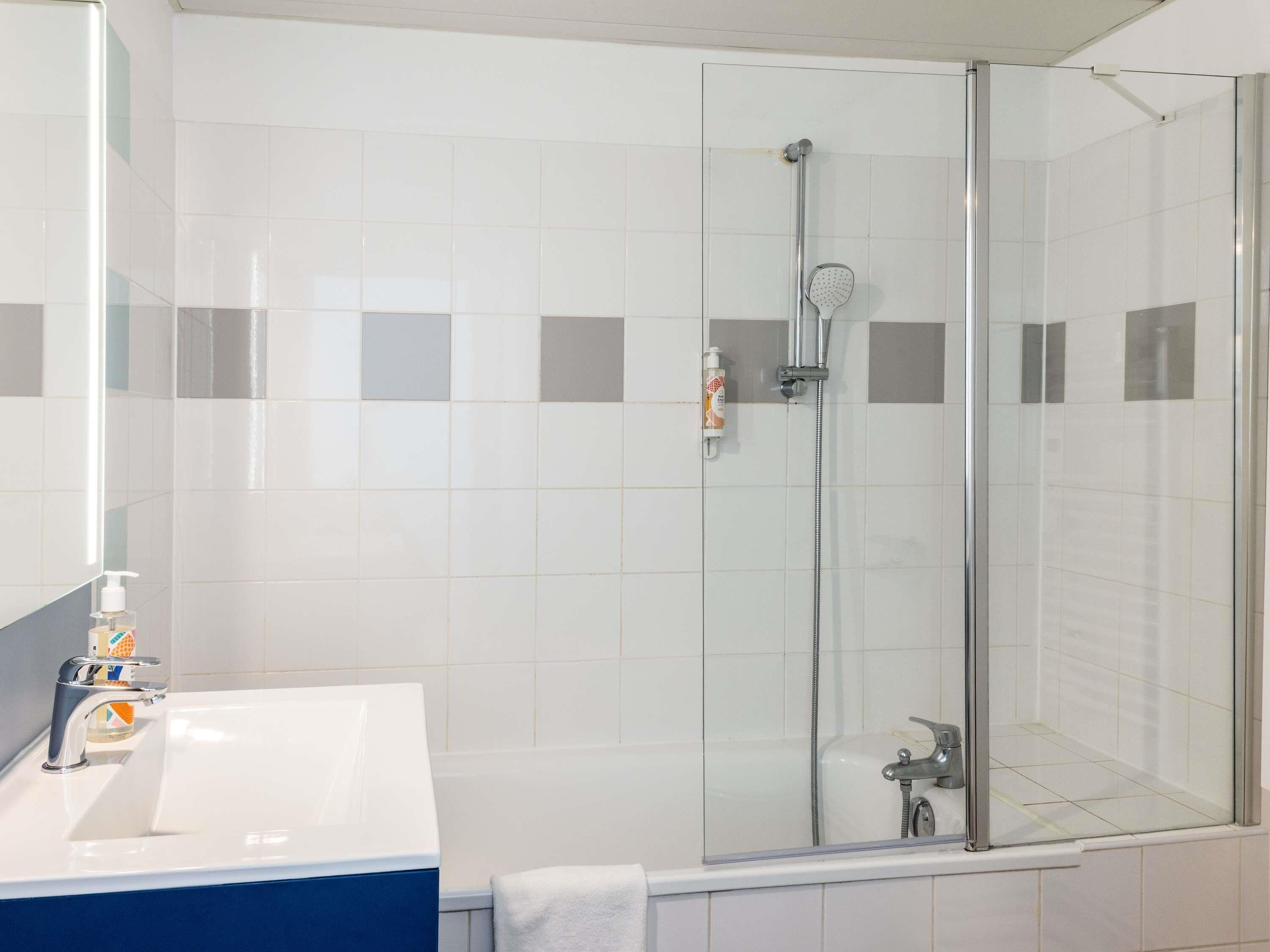 A bathroom with a glass-enclosed shower, a white sink, and a mirror.