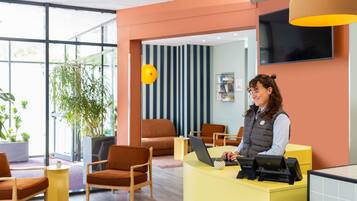 A reception desk with a laptop, a plant, and a striped wall in the background.
