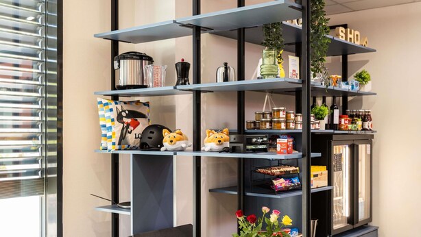 Una cocina moderna con refrigerador empotrado, repisas con utensilios de cocina y una pequeña planta.