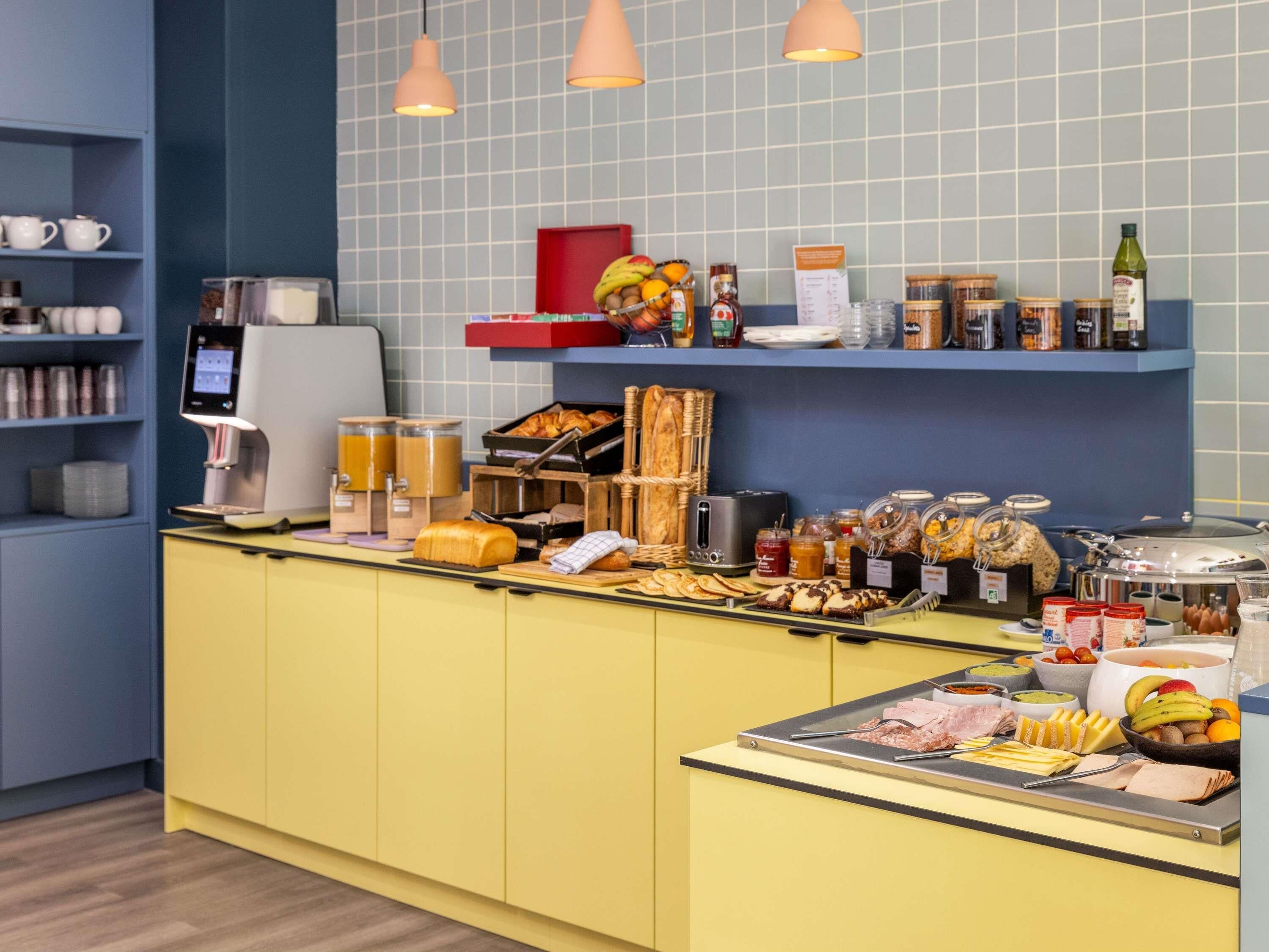 A breakfast buffet with various food items, a coffee machine, and a juice dispenser.